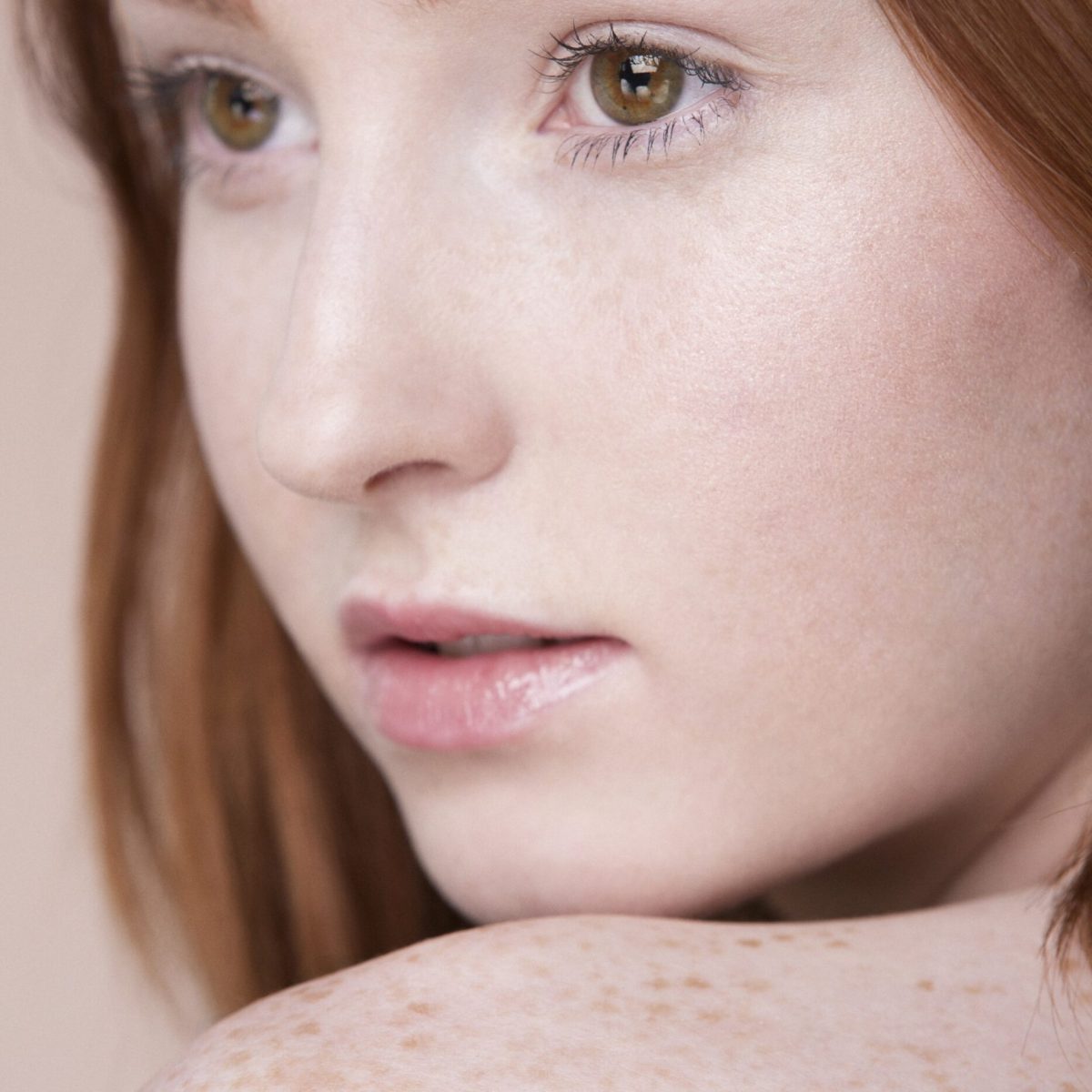 Young woman with a contemplative gaze, featuring freckles Young woman with a contemplative gaze, featuring freckles